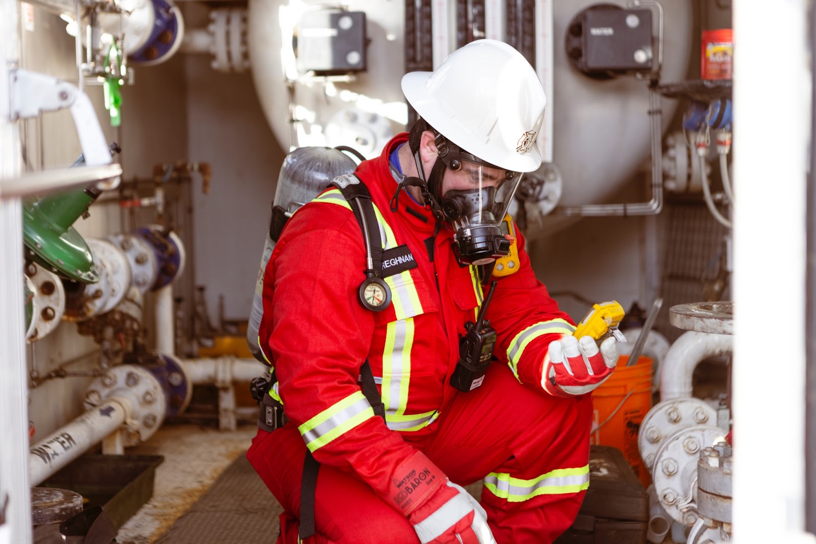 A worker looking at an H2S monitor wearing a SCBA.