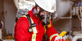 A worker looking at an H2S monitor wearing a SCBA.